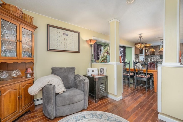 living area with a baseboard radiator, decorative columns, and dark wood-type flooring