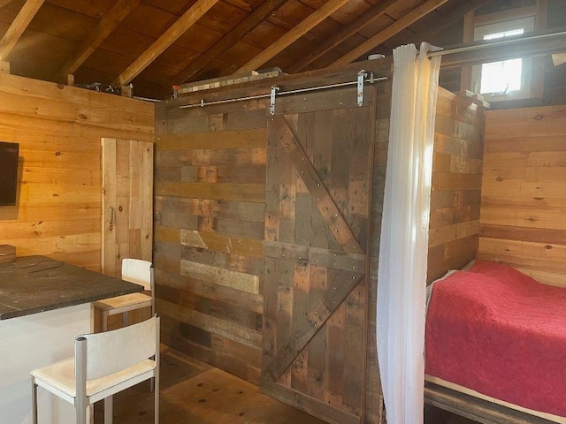 interior space featuring lofted ceiling, a barn door, wood walls, and wooden ceiling