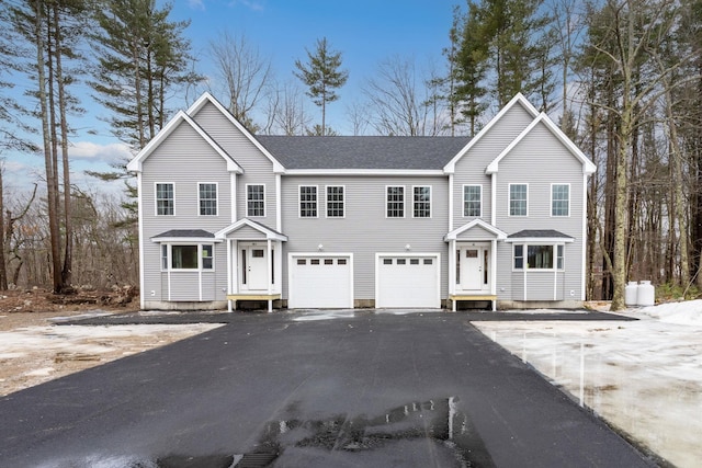 view of front facade with aphalt driveway, roof with shingles, and an attached garage