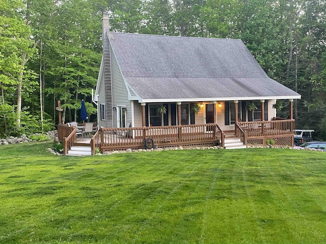 view of front of home featuring a chimney, a porch, roof with shingles, and a front yard