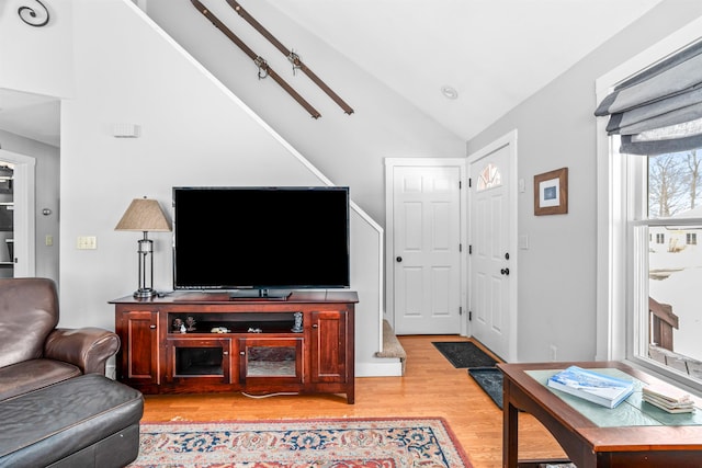 living area with light wood-style floors and lofted ceiling