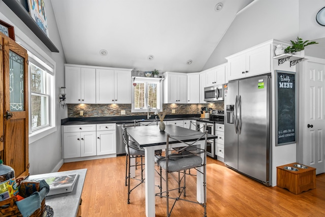 kitchen with dark countertops, white cabinetry, stainless steel appliances, and a sink