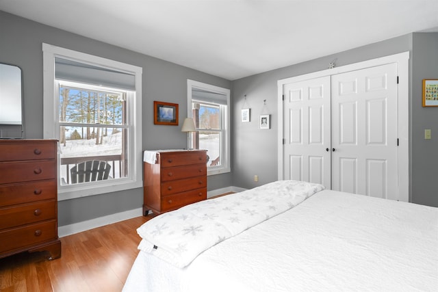 bedroom with a closet, wood finished floors, and baseboards