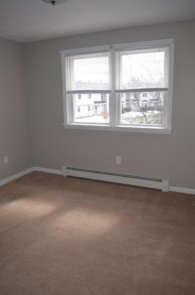 carpeted empty room with a baseboard heating unit and baseboards