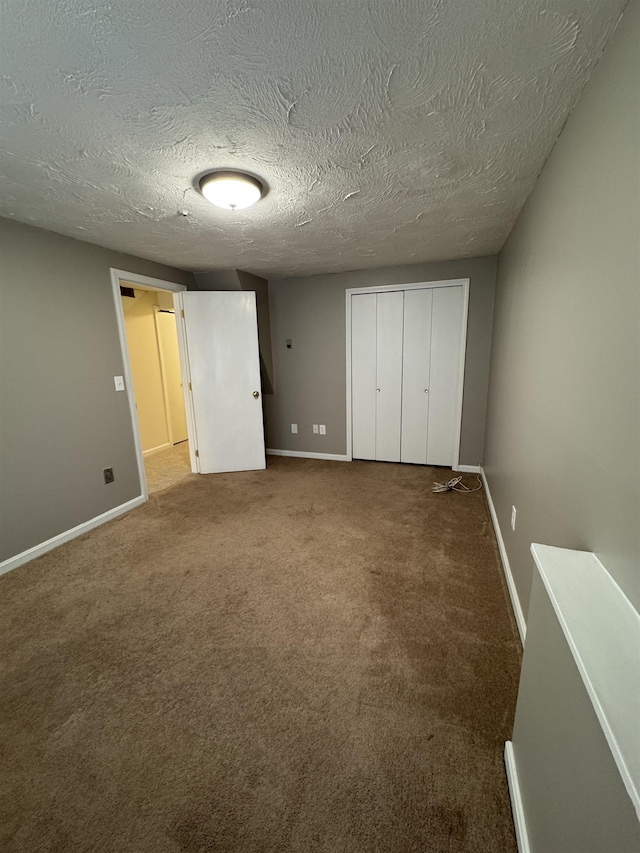 unfurnished bedroom with a closet, baseboards, a textured ceiling, and carpet flooring