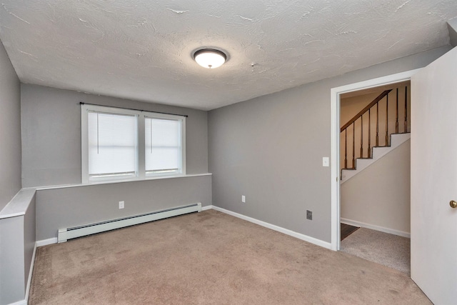 carpeted spare room featuring a baseboard heating unit, baseboards, a textured ceiling, and stairs