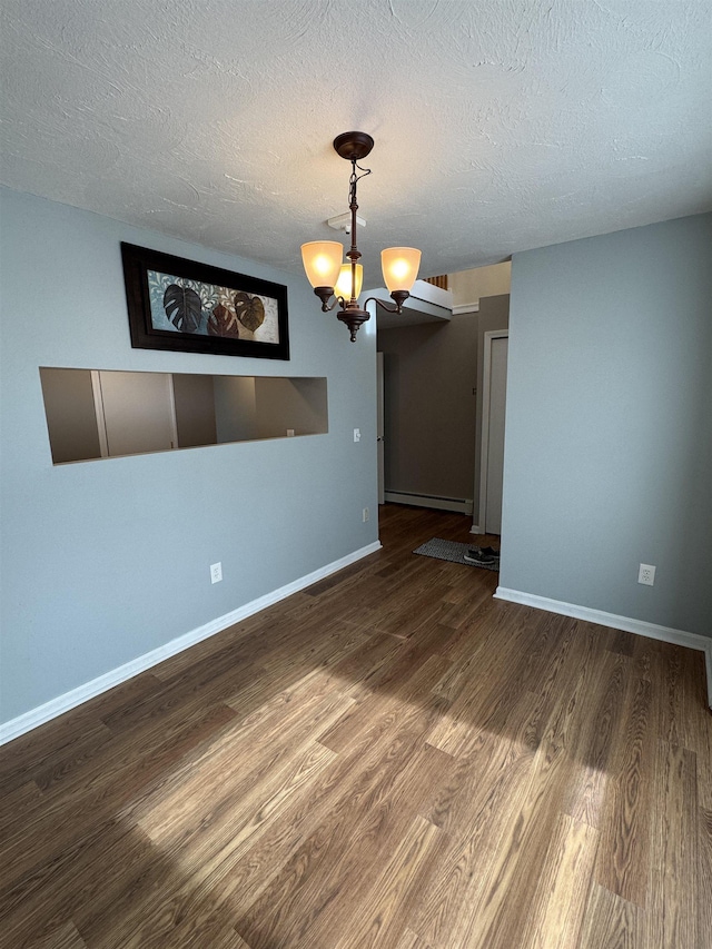 spare room with a chandelier, a textured ceiling, baseboards, and wood finished floors