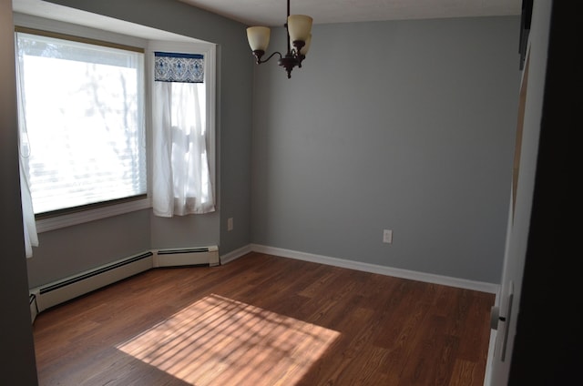 spare room featuring baseboards, baseboard heating, an inviting chandelier, and dark wood finished floors