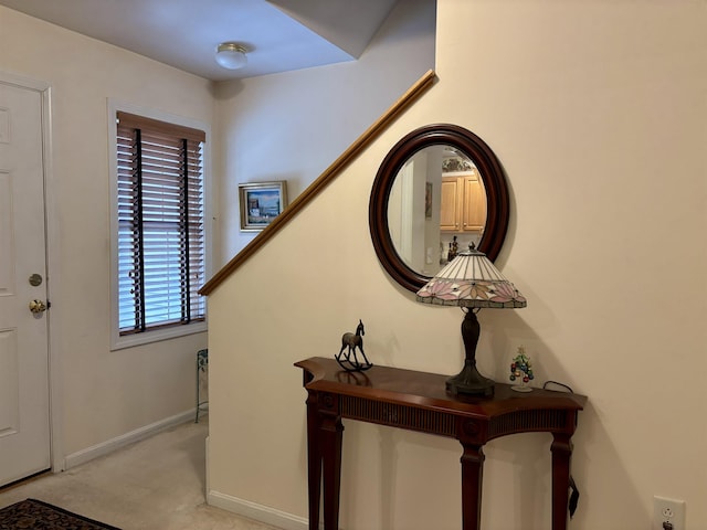 entrance foyer featuring baseboards and light colored carpet