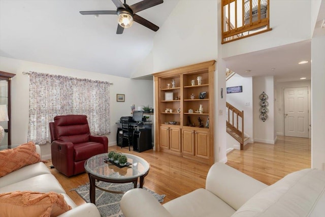 living area with a ceiling fan, high vaulted ceiling, light wood-style flooring, recessed lighting, and stairs