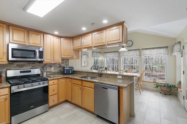 kitchen featuring a sink, appliances with stainless steel finishes, a peninsula, decorative backsplash, and vaulted ceiling