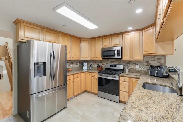 kitchen with light brown cabinetry, decorative backsplash, stainless steel appliances, and a sink