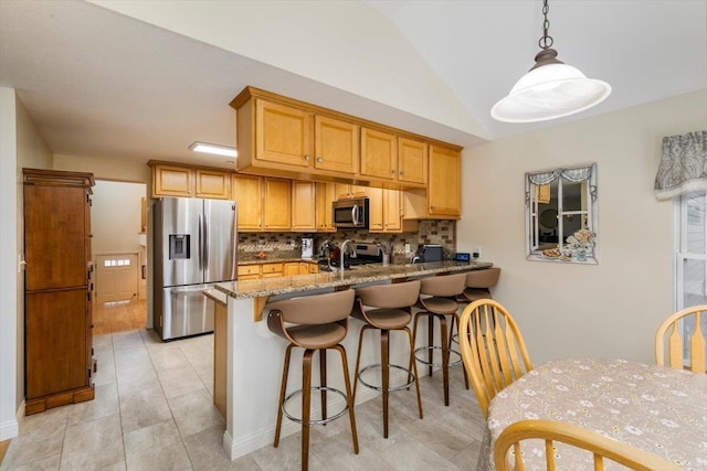 kitchen featuring light stone countertops, a peninsula, lofted ceiling, stainless steel appliances, and tasteful backsplash