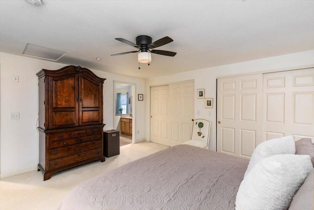 bedroom featuring connected bathroom, baseboards, multiple closets, light colored carpet, and attic access