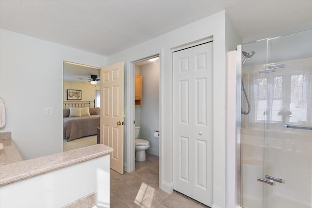 ensuite bathroom with tile patterned flooring, a shower stall, a closet, toilet, and connected bathroom