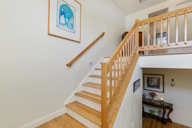 staircase featuring visible vents, wood finished floors, and baseboards