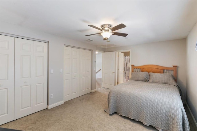 bedroom with visible vents, two closets, a ceiling fan, carpet, and baseboards