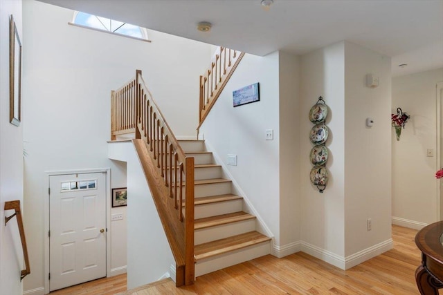 stairs with a skylight, baseboards, and wood finished floors