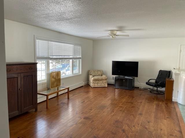 sitting room with a textured ceiling, baseboard heating, wood finished floors, and a ceiling fan