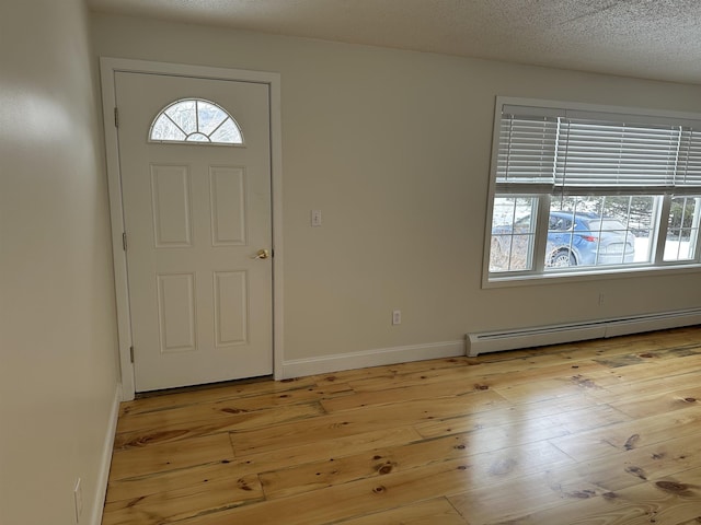 foyer entrance featuring a baseboard radiator, baseboards, a textured ceiling, and light wood finished floors