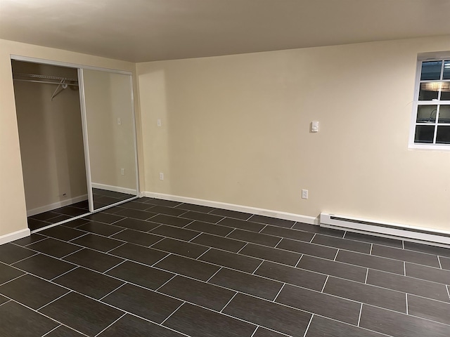 unfurnished bedroom featuring a baseboard heating unit, baseboards, and a closet