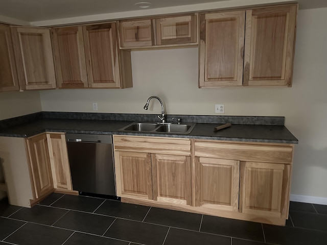 kitchen with dark countertops, a sink, baseboards, dishwasher, and dark tile patterned flooring