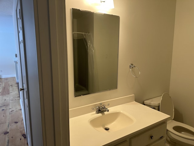 bathroom with a shower with curtain, toilet, wood finished floors, and vanity