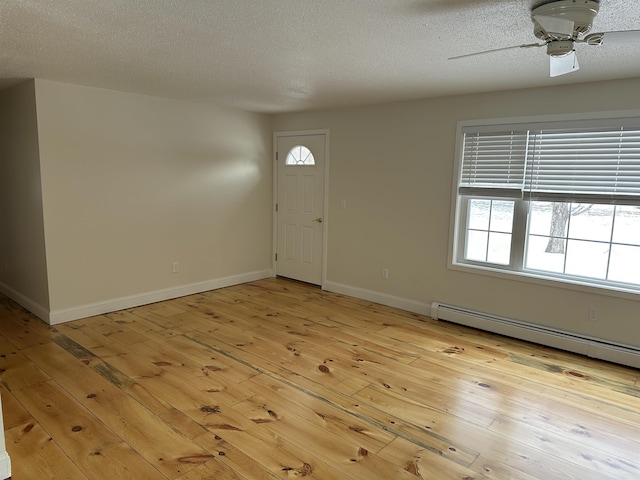 entryway with light wood finished floors, a textured ceiling, a baseboard heating unit, and baseboards