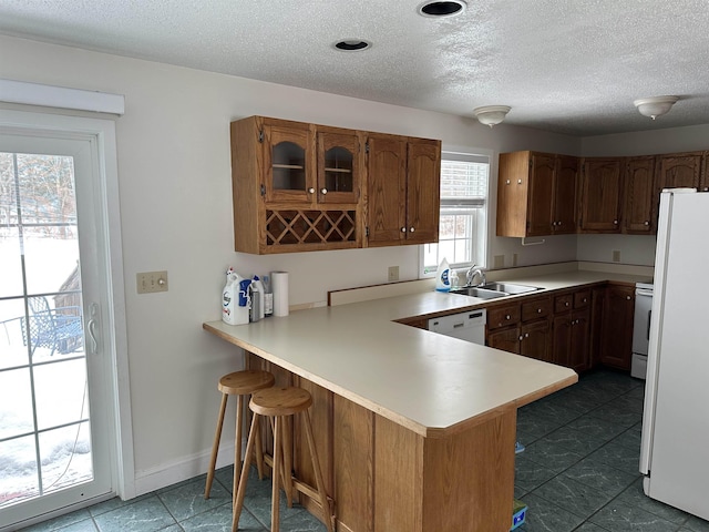 kitchen with a sink, white appliances, a peninsula, a breakfast bar area, and light countertops