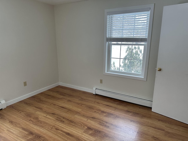 spare room with wood finished floors, baseboards, and baseboard heating