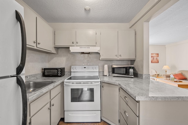 kitchen featuring white electric stove, freestanding refrigerator, light countertops, under cabinet range hood, and stainless steel microwave