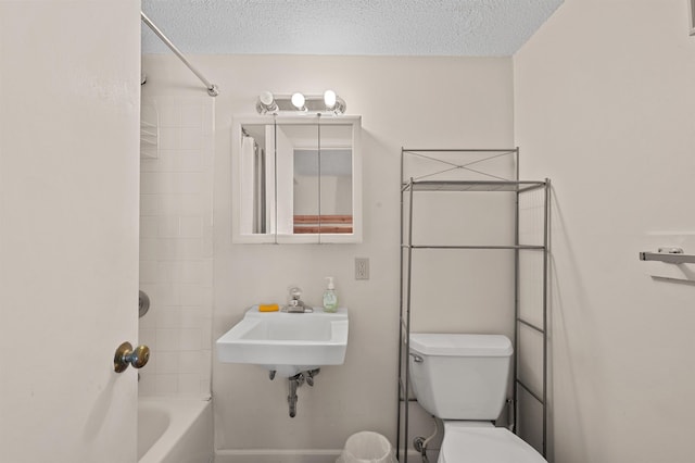 bathroom with a sink, bathing tub / shower combination, toilet, and a textured ceiling