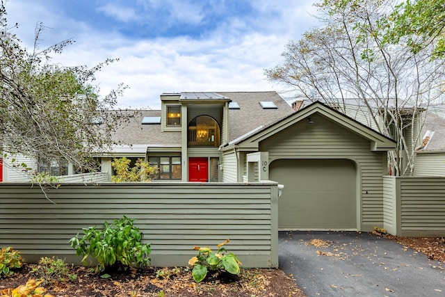 view of front of house with aphalt driveway, a garage, a fenced front yard, and roof with shingles