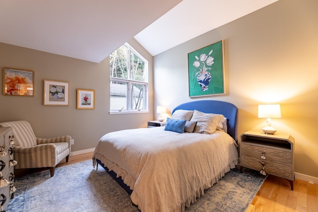 bedroom with baseboards, wood finished floors, and vaulted ceiling