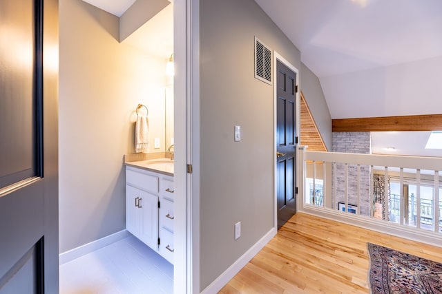 interior space featuring visible vents, baseboards, wood finished floors, and vanity