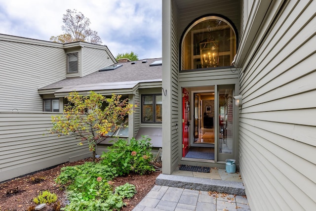 doorway to property featuring roof with shingles