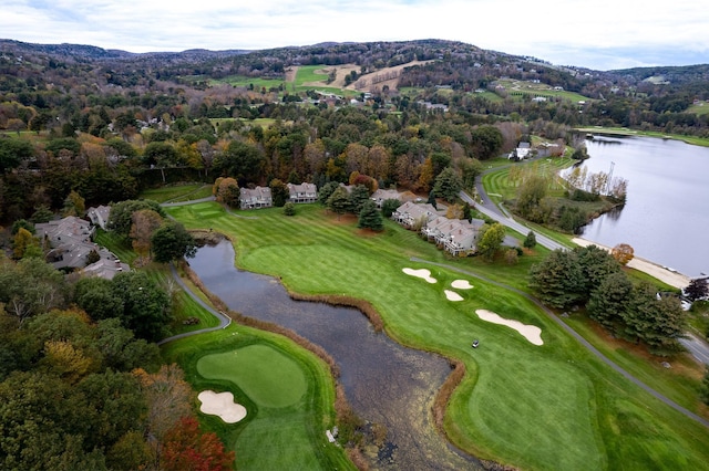 drone / aerial view featuring a wooded view, golf course view, and a water view