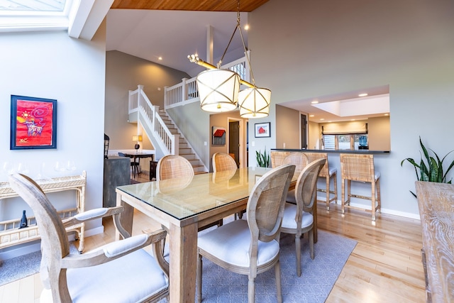 dining room with baseboards, stairs, recessed lighting, wood finished floors, and high vaulted ceiling