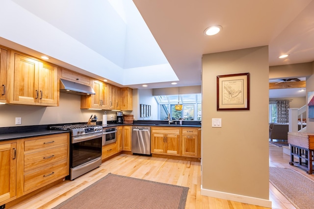 kitchen featuring light wood-style flooring, under cabinet range hood, dark countertops, recessed lighting, and appliances with stainless steel finishes