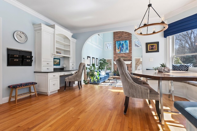 dining area with light wood finished floors, an inviting chandelier, and ornamental molding