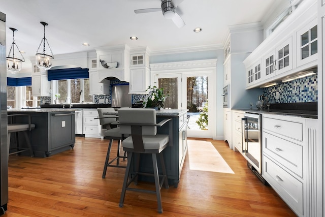 kitchen featuring oven, a center island, wine cooler, a breakfast bar area, and white cabinets