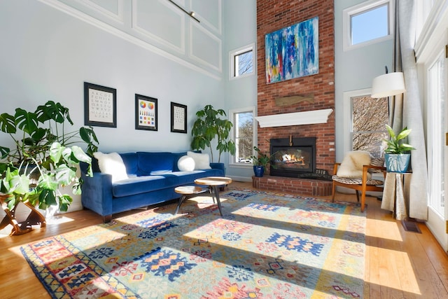 living area featuring visible vents, a fireplace, a high ceiling, and wood finished floors