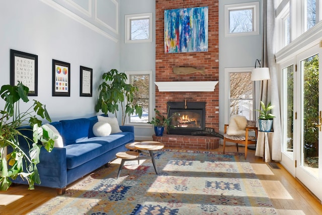 living room featuring visible vents, a brick fireplace, wood finished floors, and a high ceiling