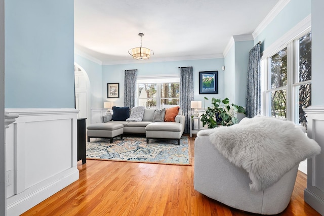 living room with arched walkways, wood finished floors, and ornamental molding