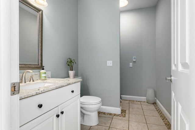 half bathroom featuring baseboards, toilet, vanity, and tile patterned flooring