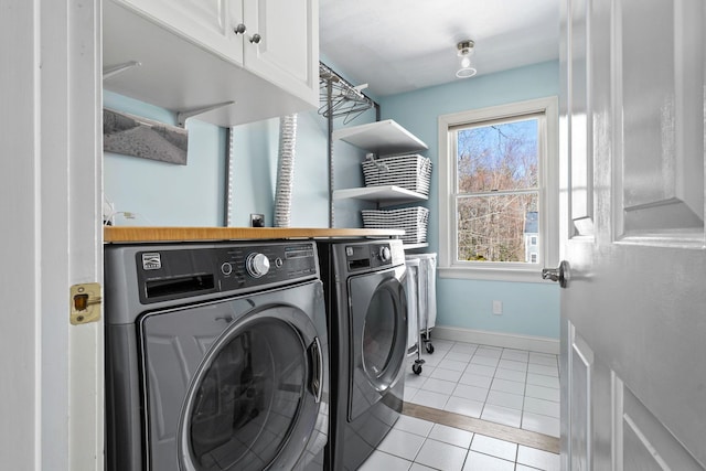 washroom with light tile patterned flooring, washing machine and dryer, cabinet space, and baseboards