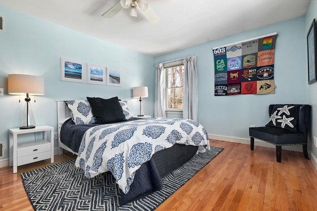 bedroom featuring ceiling fan, visible vents, baseboards, and wood finished floors