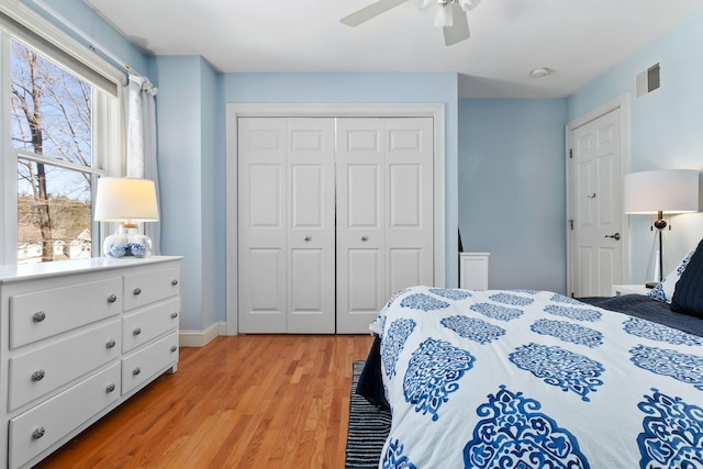 bedroom with a ceiling fan, visible vents, light wood-style floors, and a closet