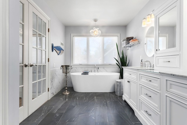 full bath with vanity, tile walls, a wainscoted wall, and a freestanding bath