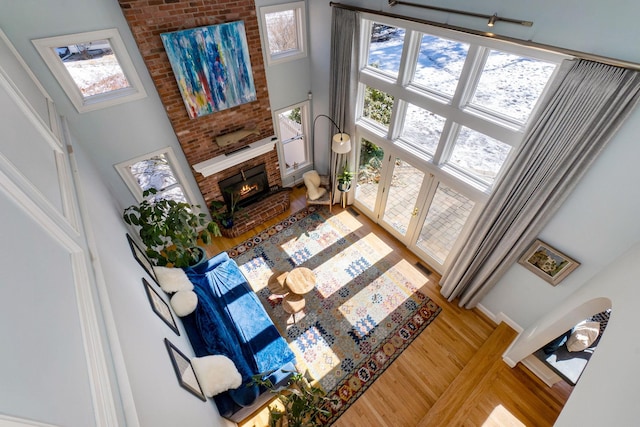 living room featuring a brick fireplace, french doors, wood finished floors, and a towering ceiling